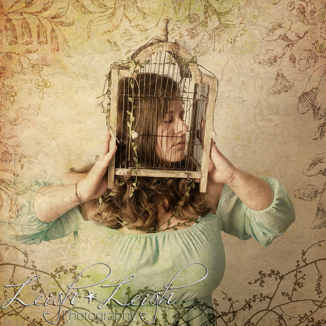 woman in a fancy dress with her head in a bird cage, surrounded by foliage on the edges