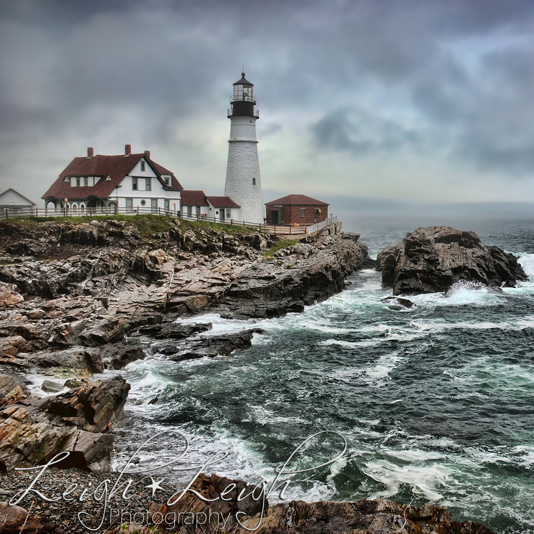 Maine light house on rocky cliff with waves crashing around it
